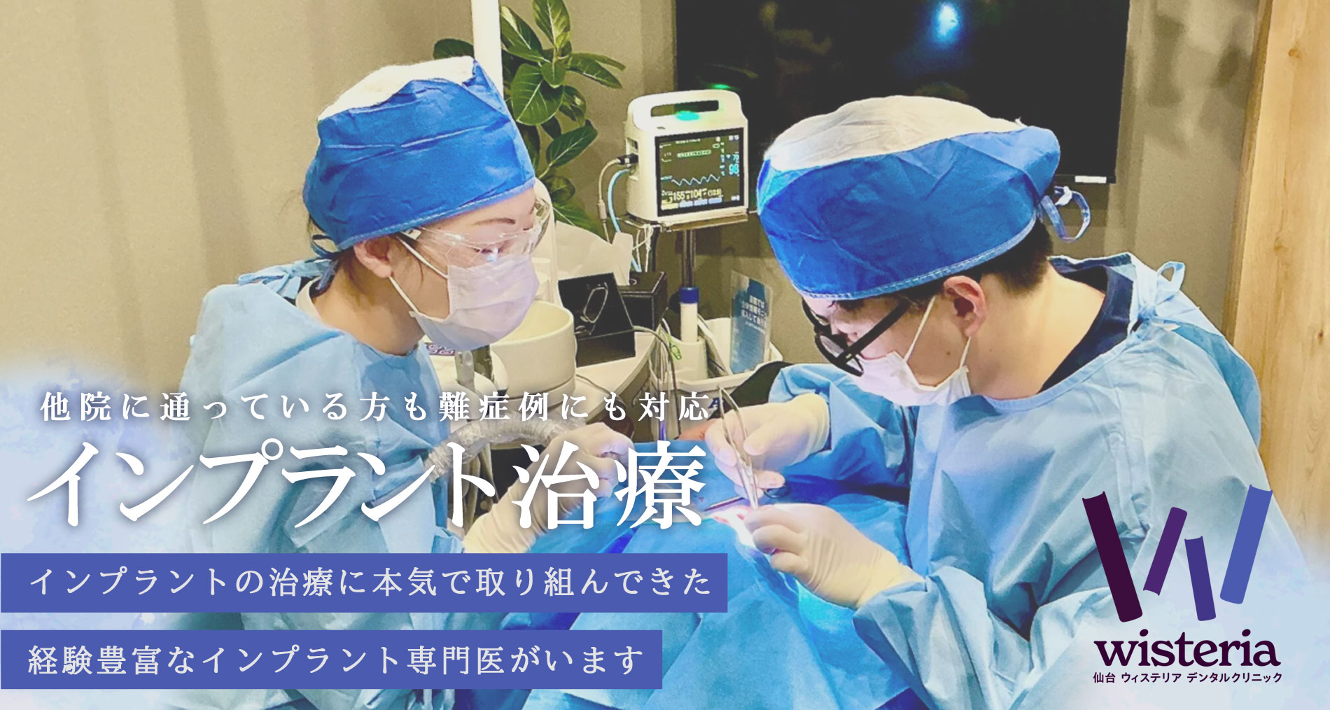 Two clinicians in blue surgical gowns and masks perform a dental implant procedure at a patient’s mouth, with monitoring equipment nearby.